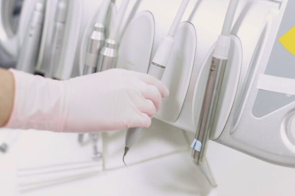 Close-up of a gloved hand operating dental tools in a sterile clinic environment.
