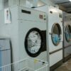Interior view of industrial laundry machines in a facility with linens being washed.