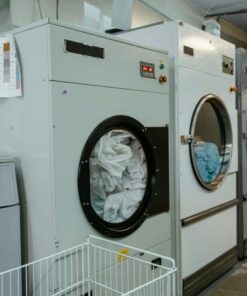Interior view of industrial laundry machines in a facility with linens being washed.