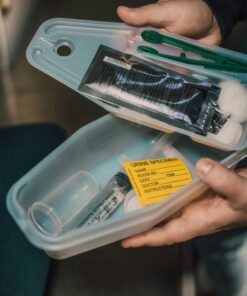 Close-up of medical kit containing syringe and urine specimen label.