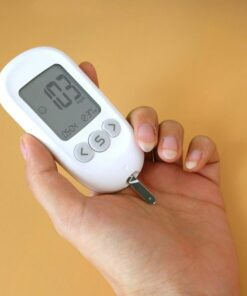 Close-up view of a blood glucose meter in hand measuring glucose levels.