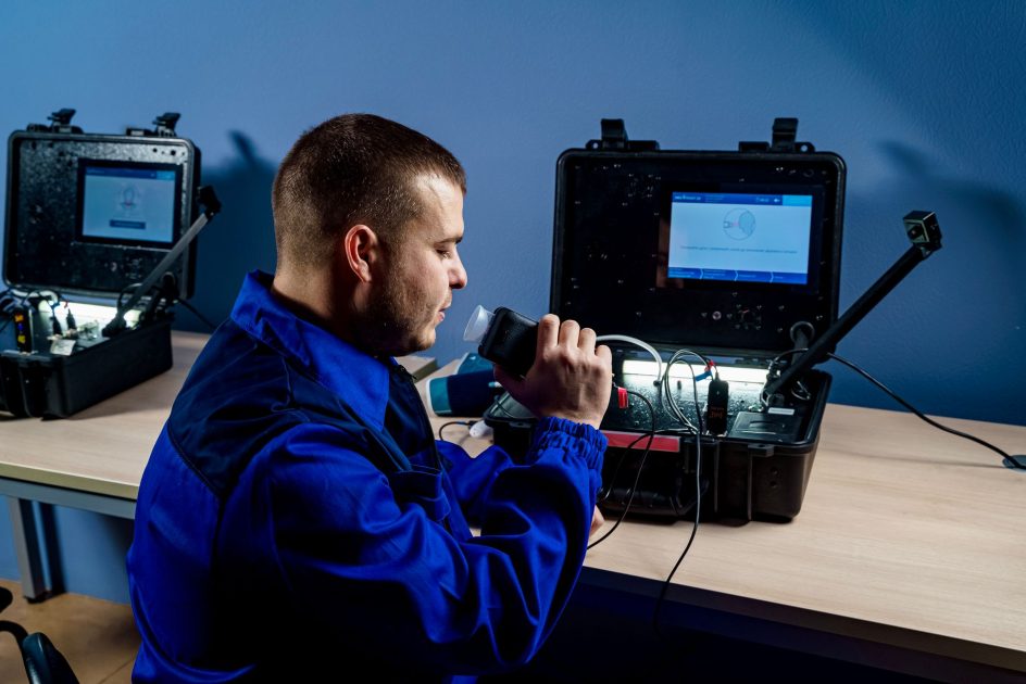 portable spectrophotometer - MedPoint 24 A technician in blue uniform using portable diagnostic equipment indoors.