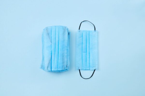 Two blue surgical masks on a light blue background, highlighting personal protection.