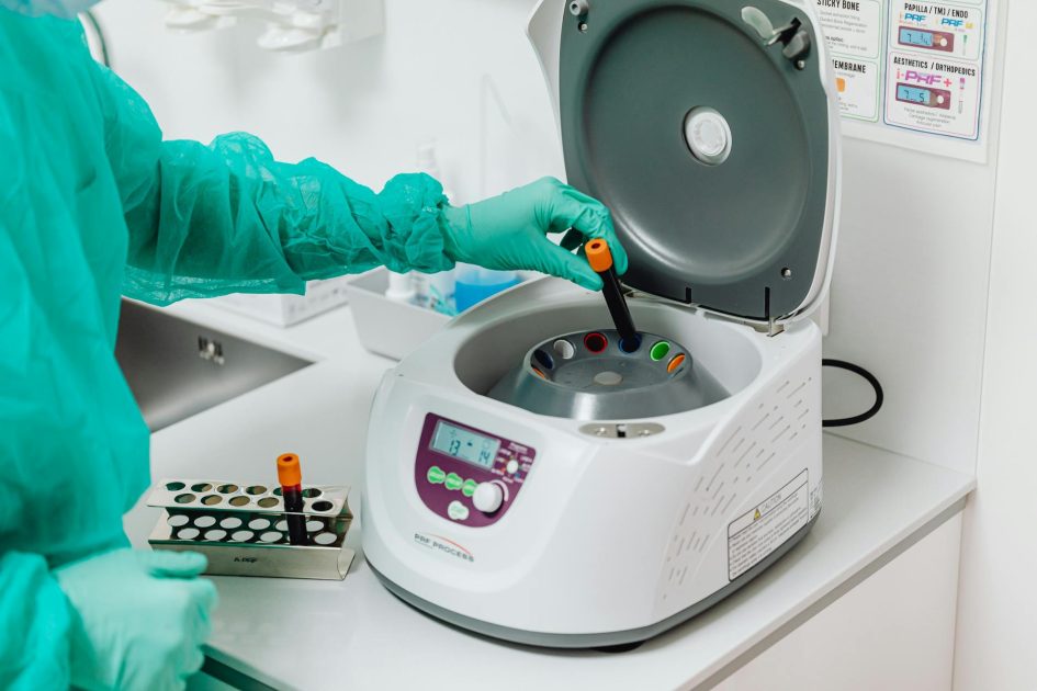 7 Fitur Protein Transfer System Terbaik untuk Western Blotting 1 A healthcare professional operates a centrifuge machine in a laboratory, ensuring sterile medical procedures.