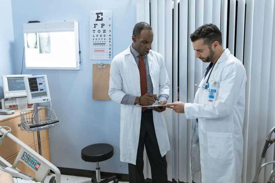 RS Bali Promosikan Dokter Singapura: 9 Fakta & Panduan 2025 1 Two doctors in lab coats discussing a patient's medical chart in a hospital setting.