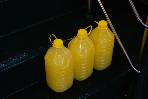 Three large yellow juice containers placed on a metal-railed staircase.