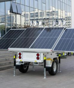 A mobile solar panel trailer parked outdoors by a modern building, showcasing renewable energy technology.