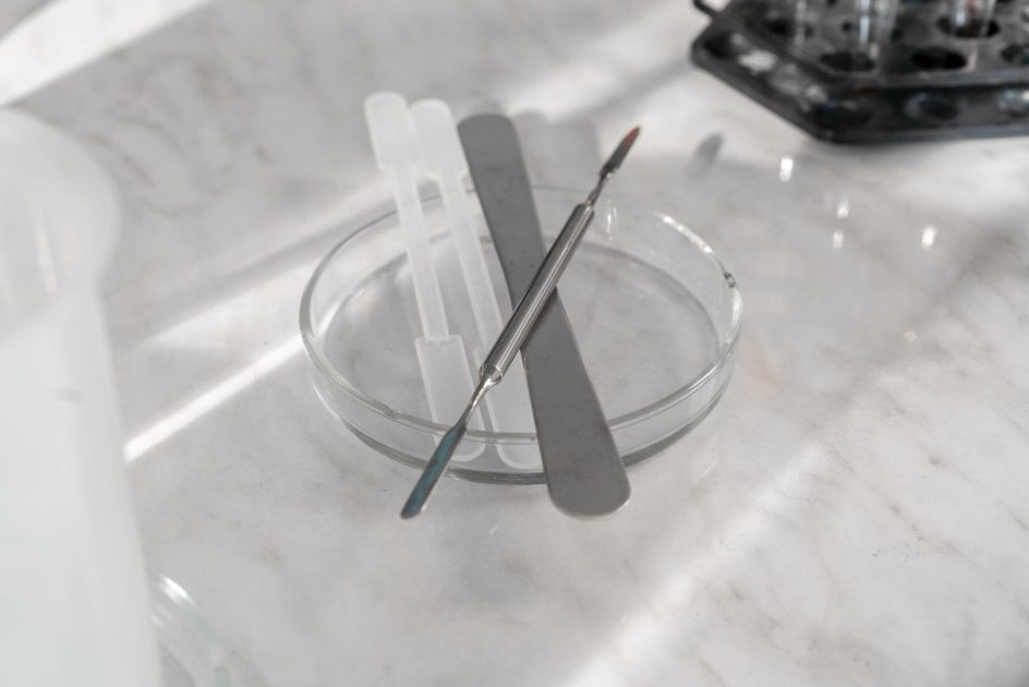 Spatula Kedokteran Gigi: 5 Jenis dan Fungsinya 1 A detailed close-up of various laboratory tools placed on a glass plate, ideal for scientific research themes.