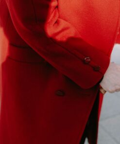 An elderly person in a red coat holds a cane, reflecting elegance and style.