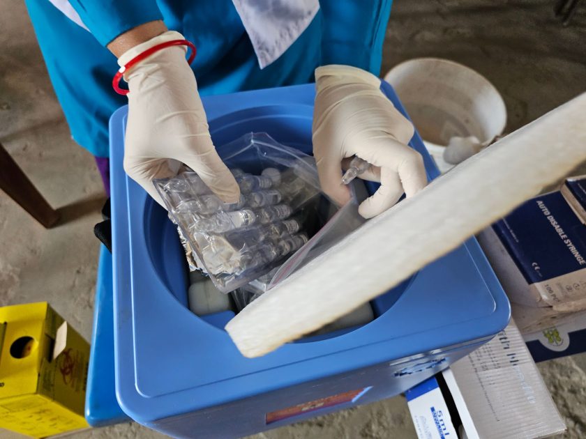 Healthcare worker using gloves handling medical vials in a laboratory setting.