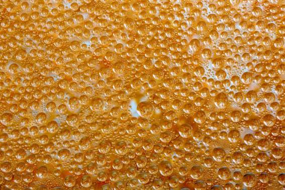 Macro shot of dew droplets on an orange-colored textured surface, creating a vibrant pattern.