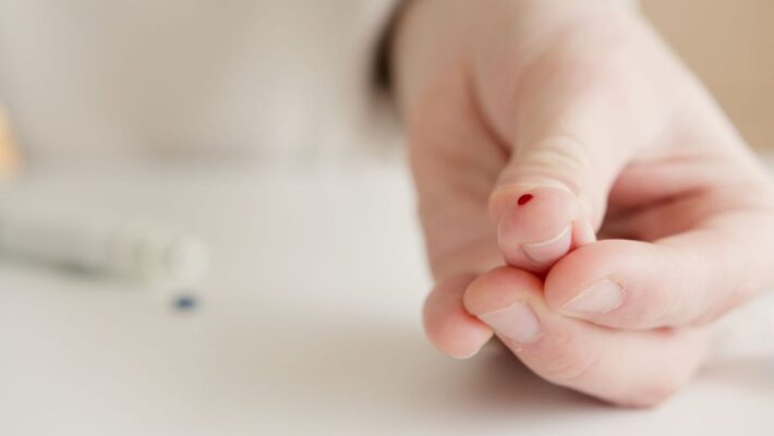 Close-up of a hand with a finger prick for home blood testing. Ideal for health and medical themes.