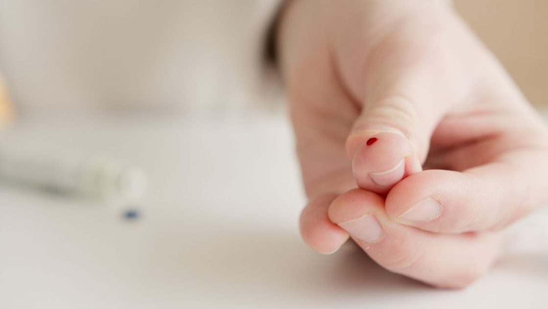 Close-up of a hand with a finger prick for home blood testing. Ideal for health and medical themes.