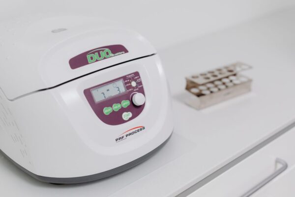 Close-up of a modern laboratory centrifuge on a sterile white surface, used in medical testing.