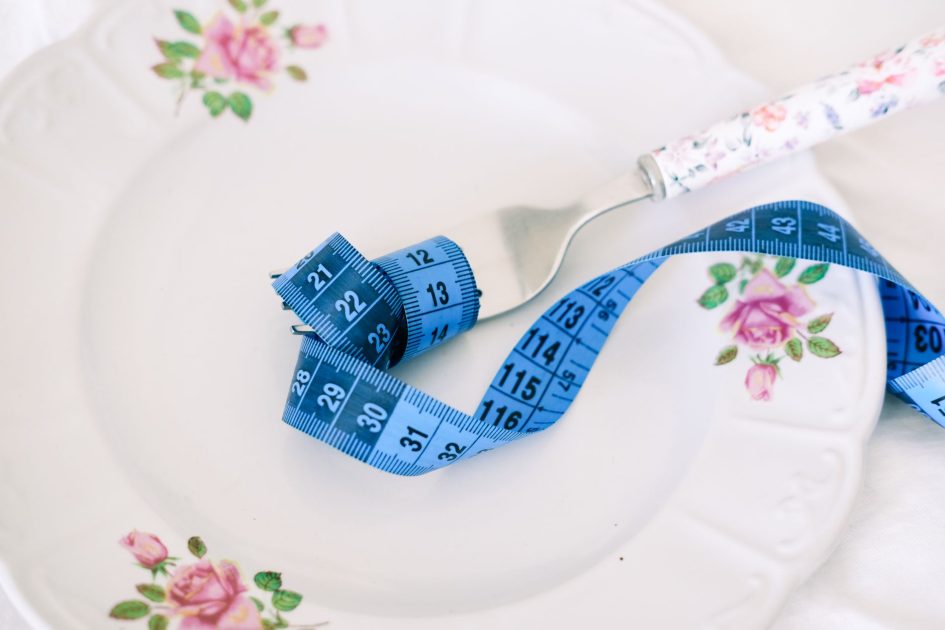 Diet Tak Harus Mahal Makan: 7 Panduan Gizi Sehat di Warteg 1 A floral plate with a fork and blue measuring tape symbolizing dieting or healthy eating.