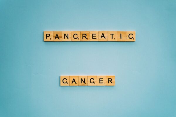 Wooden tiles spelling pancreatic cancer on blue. Health awareness concept.