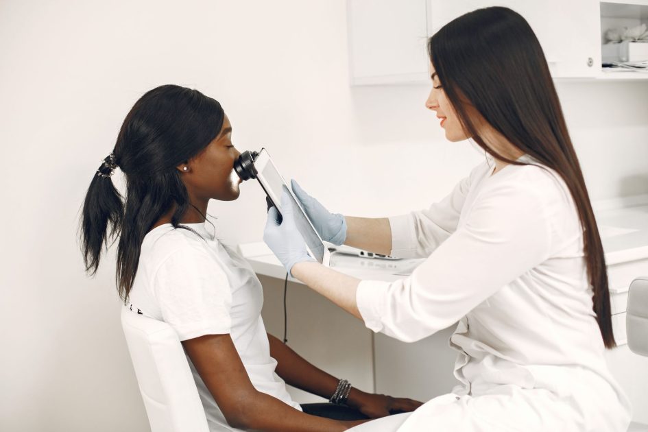 A specialist performing a skin analysis on a patient using advanced equipment in a clinic.
