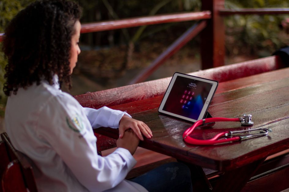 Lewat VIOLA BPJS Kesehatan Kini: 7 Panduan Akses Layanan di Daerah 3T 1 Female healthcare worker uses a tablet with stethoscope outdoors in São Paulo, Brazil.