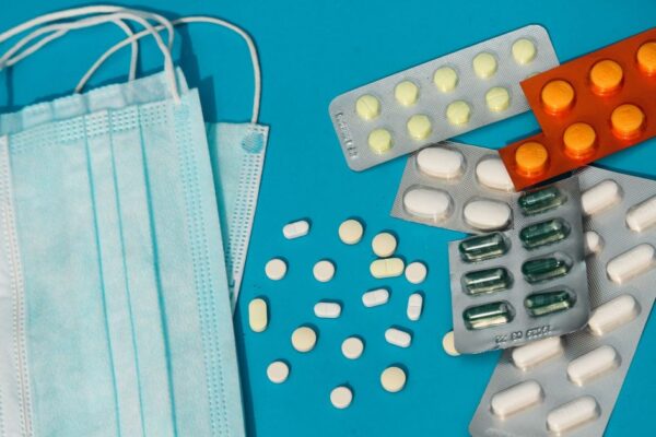 Flat lay of face masks and assorted pills on a vibrant blue surface symbolizing health and protection.