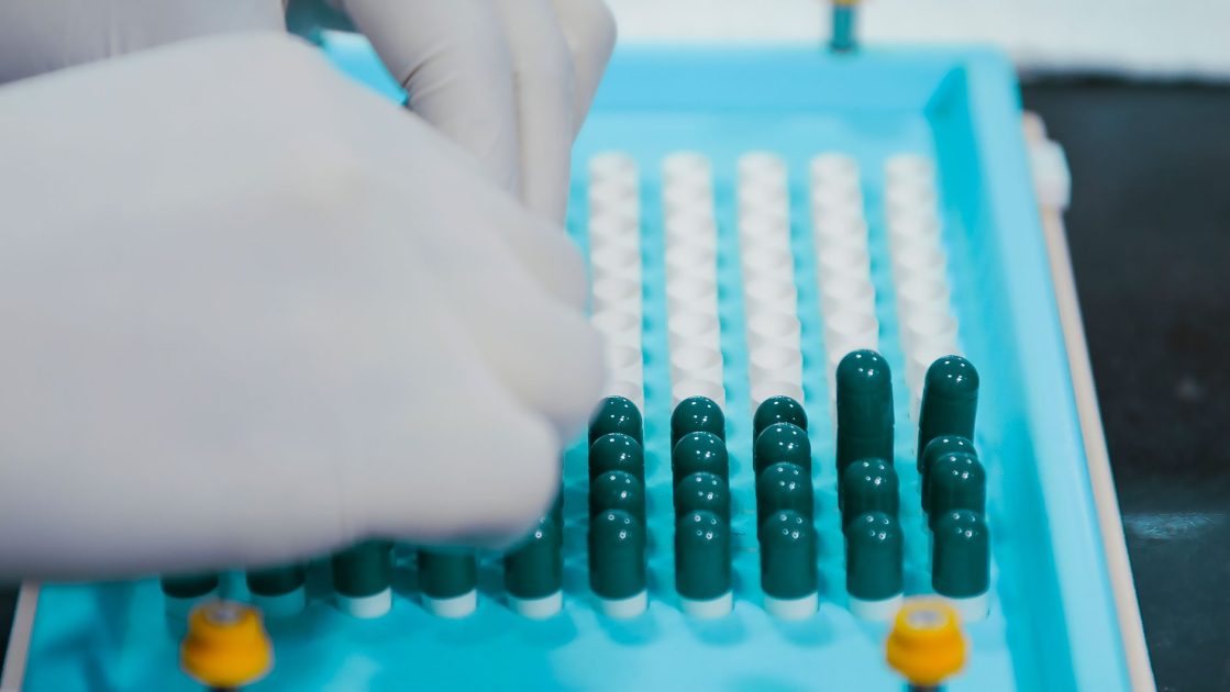Planetary Mixer Vacuum SK 300TVS: 5 Aplikasi Industri & ROI 1 Close-up view of gloved hands arranging capsules on a sterile tray, indicative of pharmaceutical practices.