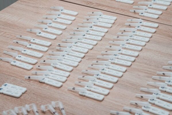 Multiple COVID-19 test kits displayed neatly on a wooden table indoors.