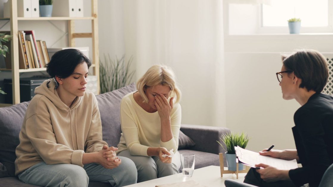 Jangan Sepelekan Mom Shaming: 7 Dampak Psikologis Ibu 1 Emotional family therapy session with a therapist indoors, conveying connection and support.