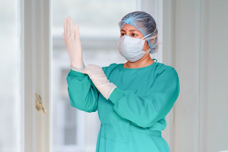 WHO Nyatakan Wabah Hantavirus Kapal: 7 Panduan Lengkap Pencegahan 1 Surgeon in a scrub suit wearing gloves and mask in hospital setting, ready for surgery.