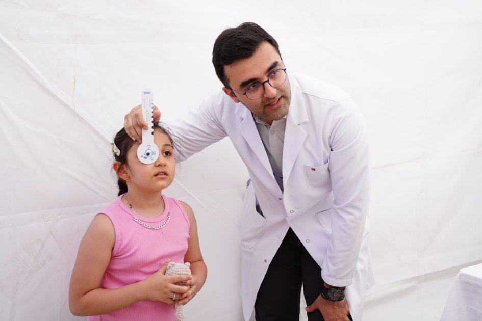 Bukan Cuma Jantung, Obesitas Anak: 7 Dampak Kesehatan Tersembunyi 1 A doctor conducts a vision test on a young girl using an eye chart in a clinical setting.