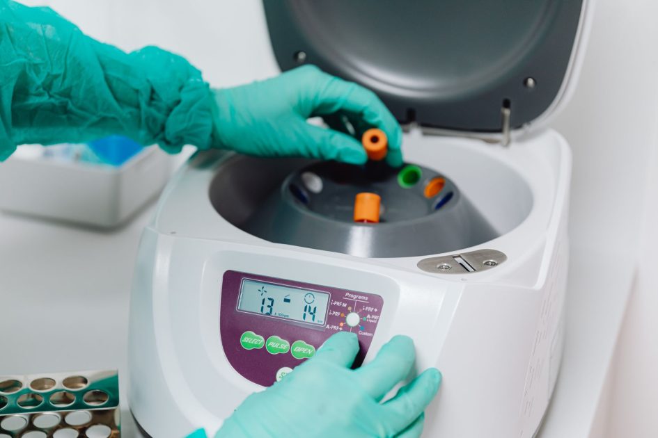 7 Tipe Centrifuge Lab: Klinik, Research & Microlab Banding RPM, Kapasitas 1 A close-up of a lab technician using a centrifuge to process blood samples in a medical laboratory.