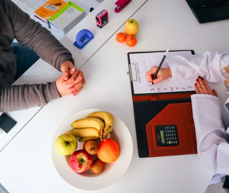 Dokter Gizi Ungkap Efek Terlalu: 7 Dampak & Solusi Sehat 1 Top view of a dietitian planning a healthy diet with fresh fruits on the table, focusing on health and nutrition.