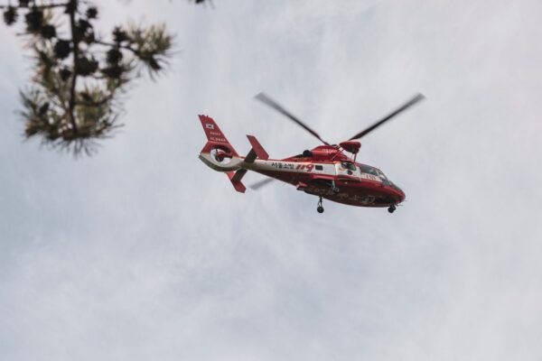 Red and white rescue helicopter flying in the sky, captured outdoors.