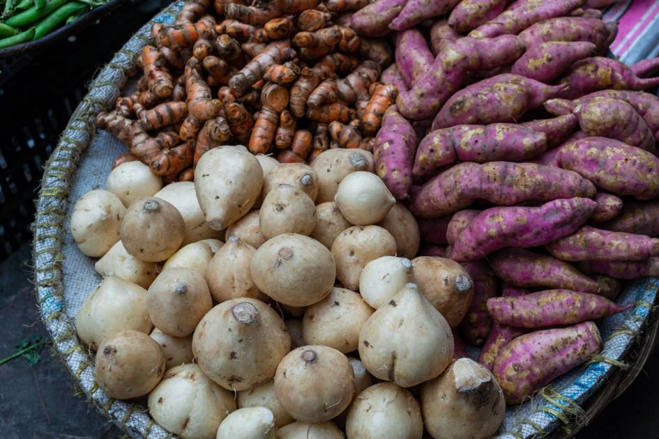 Ibu Kimpul Kenalkan Umbi-Umbian: Panduan Gizi Lokal Terlengkap 2024 1 A variety of fresh root vegetables displayed in a traditional market basket in Dhaka, Bangladesh.