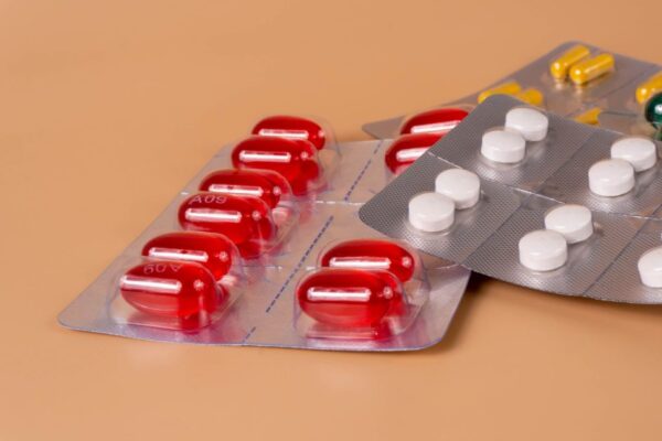 Various pills and capsules in blister packs on a solid orange background.