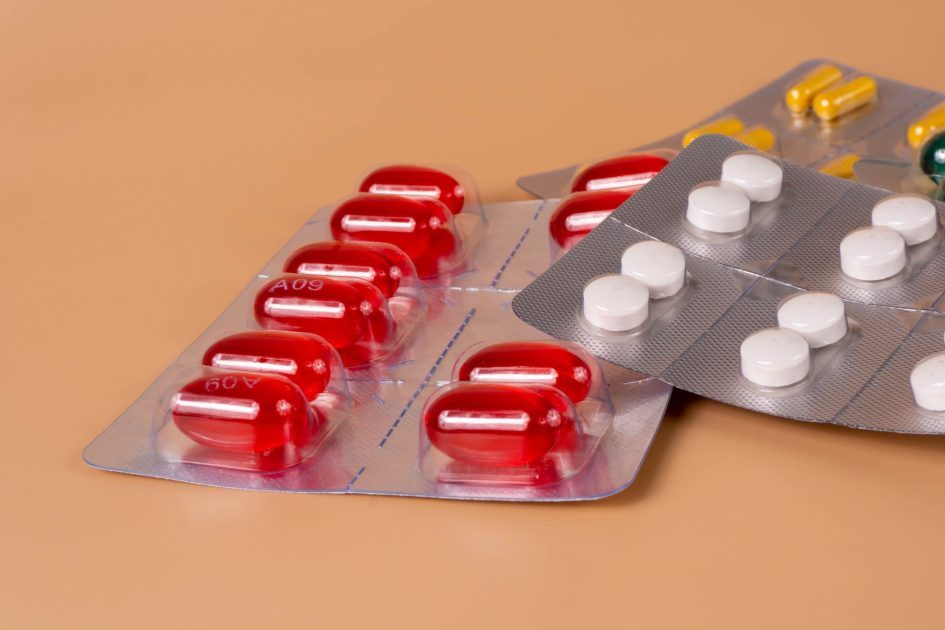 Kementerian Kesehatan Mempercepat Penyelesaian Rancangan: 5 Strategi Rantai Pasokan 1 Various pills and capsules in blister packs on a solid orange background.