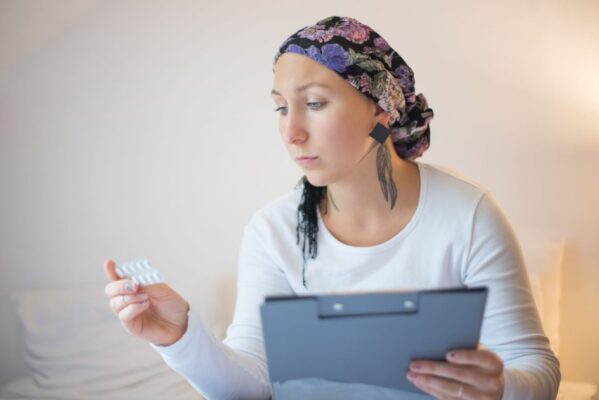 Woman with headscarf in bedroom reviews medication, symbolizing hope and recovery.