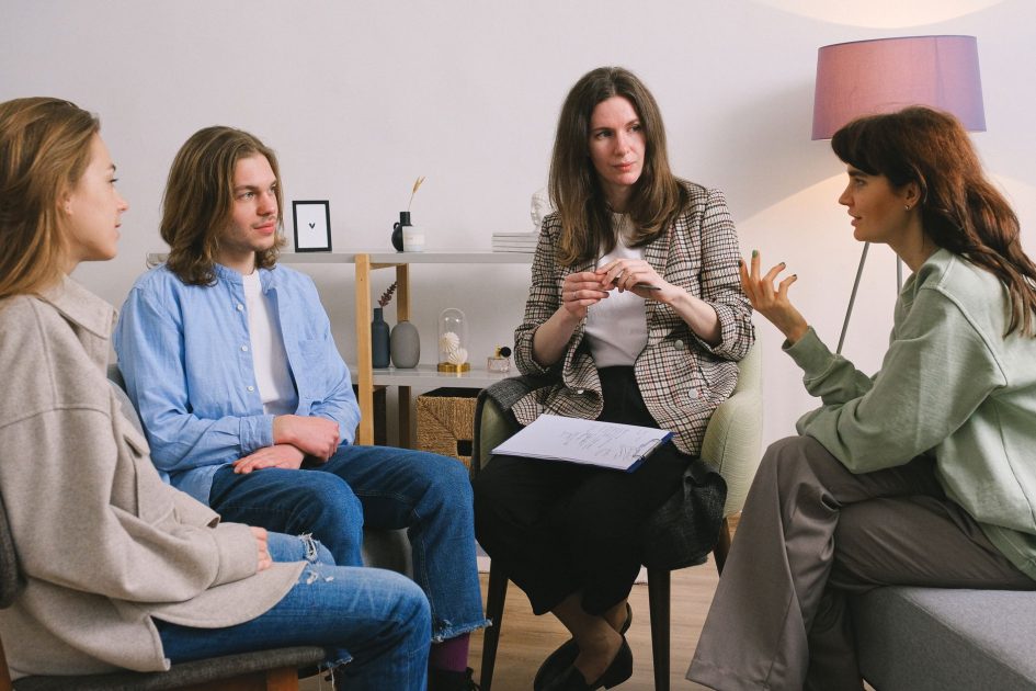Latihan Upacara Jadi Terapi Bagi ODGJ: Panduan 7 Manfaat 1 Female in casual clothes sitting on sofa and talking with psychologist and other people in group