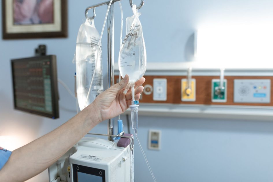 Menkes BGS Bukan Dokter Bisakah Jadi Dirjen WHO? 7 Fakta 1 Close-up image of an IV drip and hand in a hospital room, illustrating medical care.