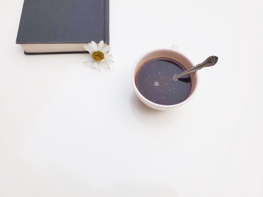 Minum Kopi Hitam Setiap Pagi: 7 Panduan Lengkap Panjang Umur 1 A serene scene of a coffee cup, book, and daisy on a white background.
