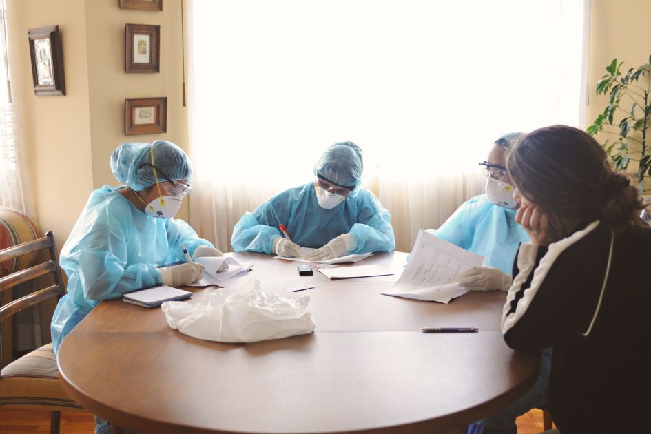 Nakes Hina Pasien BPJS Majelis: 8 Solusi Perlindungan Hak 2024 1 Medical team in protective equipment discussing at a table indoors.