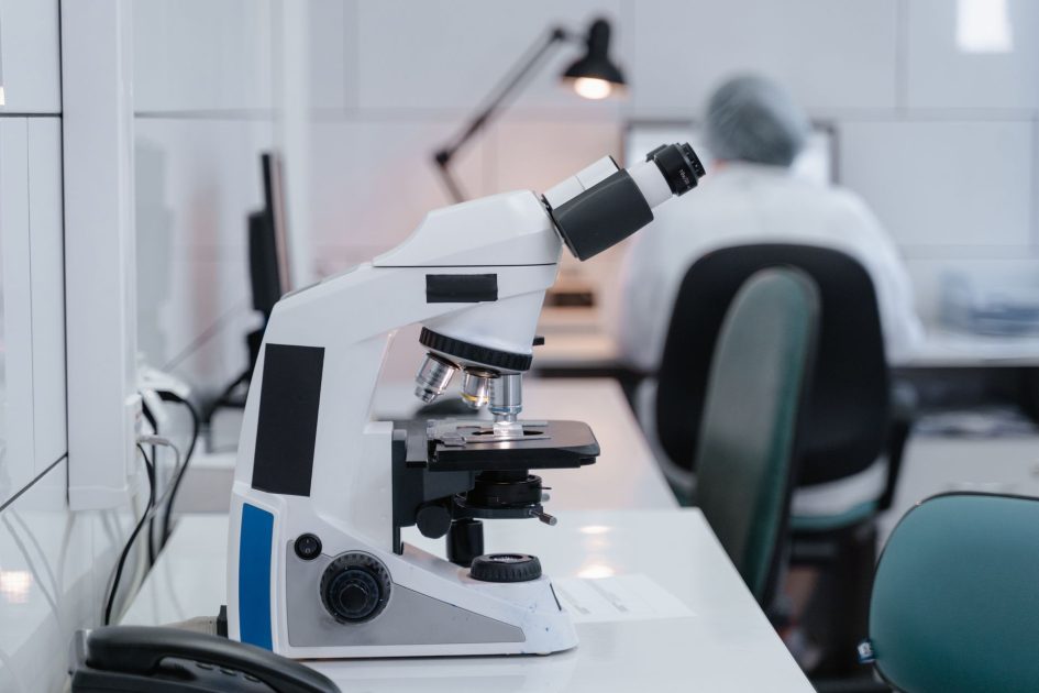 Pemeriksaan Laboratorium Modern Dinilai Penting: 7 Alasan Utama 1 Close-up of microscope on desk in a modern laboratory with scientist working in the background.