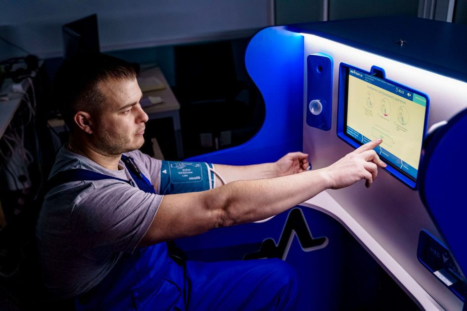 Pria 18 Tahun Pecahkan Rekor: 7 Rahasia Kesehatan Optimal Generasi Muda 1 A man uses a touch screen for a telemedicine health check in a modern setting.