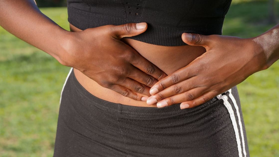7 Hal Ramai Dibahas Medsos: Terjadi Tubuh Saat Usus Buntu 1 Close-up of a person holding their stomach, indicating abdominal pain outdoors.