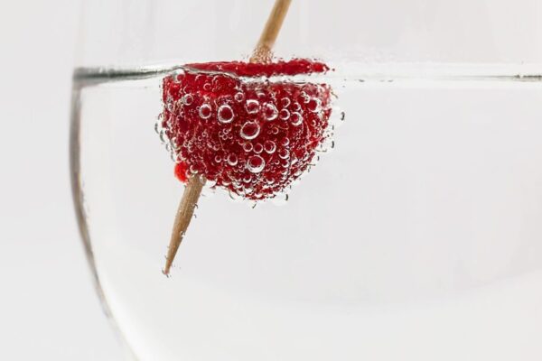 Close-up of a raspberry in sparkling water, highlighting freshness and effervescence.