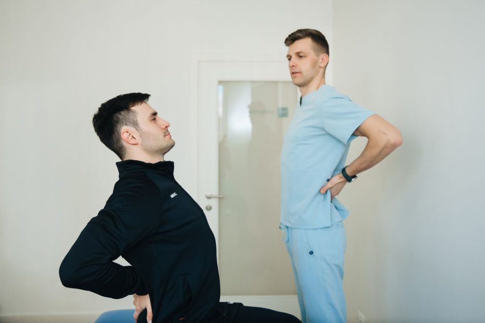 Sering Scrolling Sambil Duduk Berjam? 7 Dampak & Solusi Kesehatan 1 A physiotherapist instructs a patient on back exercises in a clinic setting.
