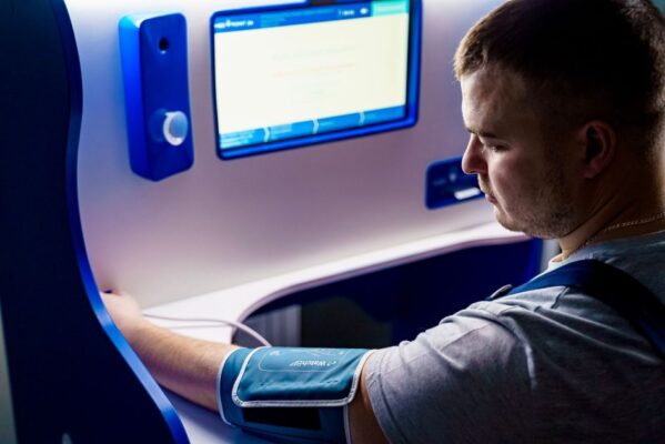 Adult measuring blood pressure with a modern digital monitor indoors.