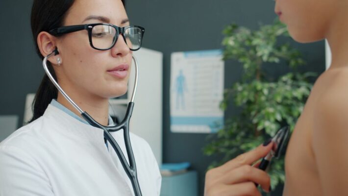Doctor conducting a health checkup on a child using a stethoscope indoors.
