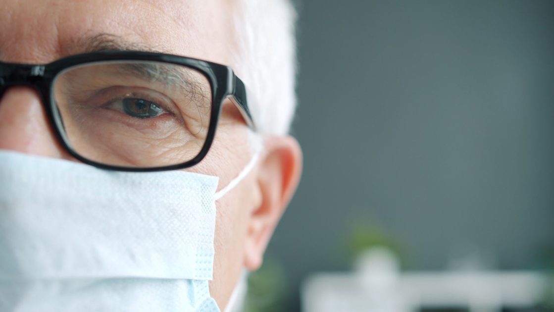 A senior man wearing glasses and a face mask, highlighting his eye for health safety.
