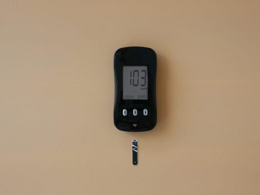 Close-up of a digital blood glucose meter displaying blood sugar level in a healthcare setting.