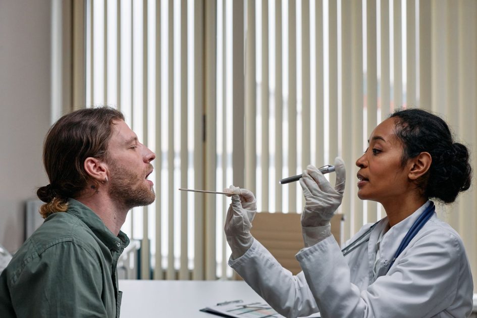 Benarkah Makan Biji Cabai Jambu Picu Usus Buntu? 7 Fakta 1 A doctor examining a patient's throat in a clinical setting, highlighting professional healthcare.