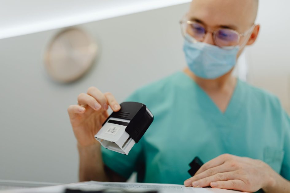 BPJS Kesehatan Minta Faskes Tak Sekadar Layani: 7 Standar Kualitas 2025 1 Healthcare worker stamping documents in a clinic setting, ensuring efficient workflow.